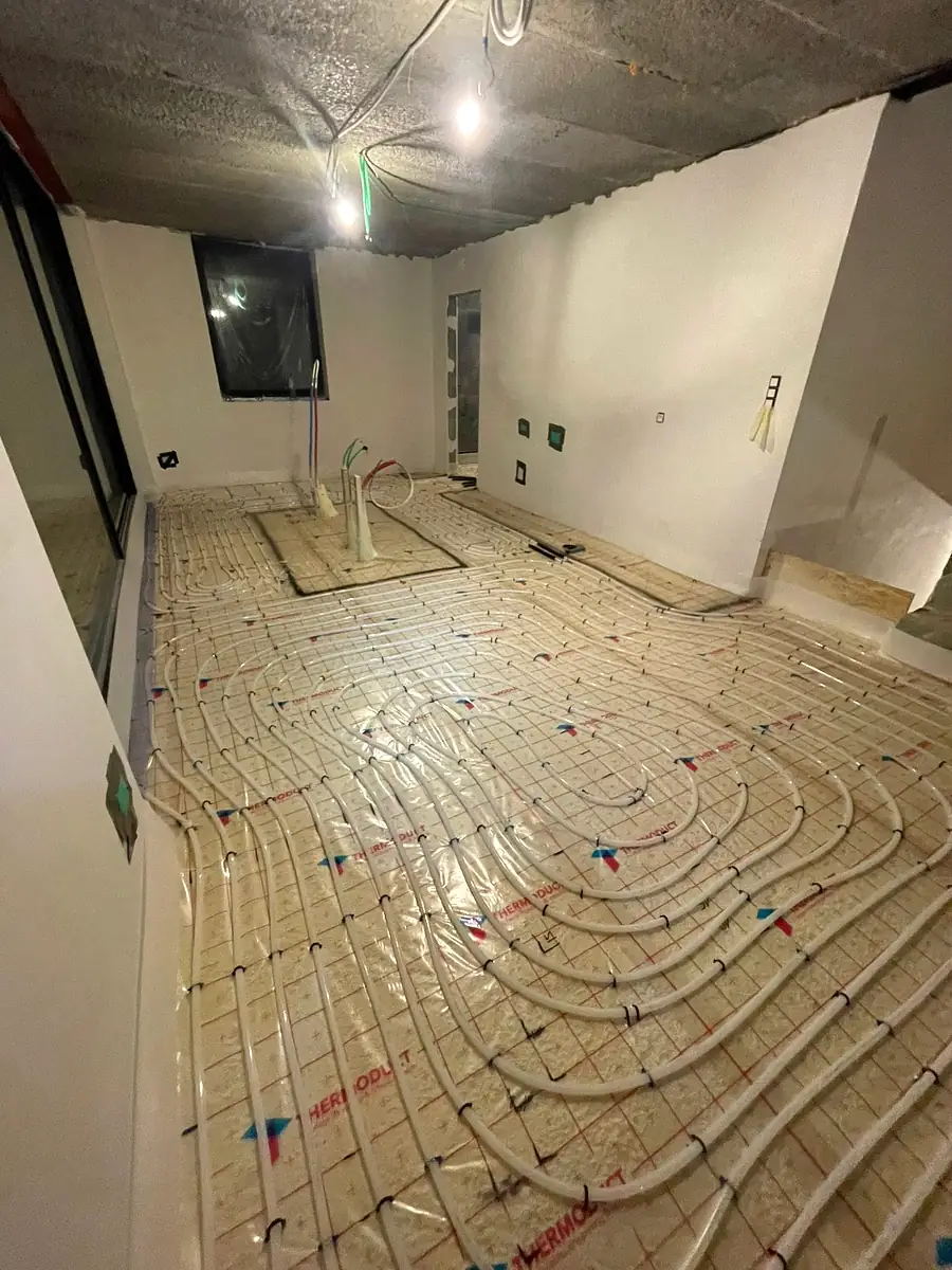 Boucles de chauffage au sol posées dans une pièce de vie en construction