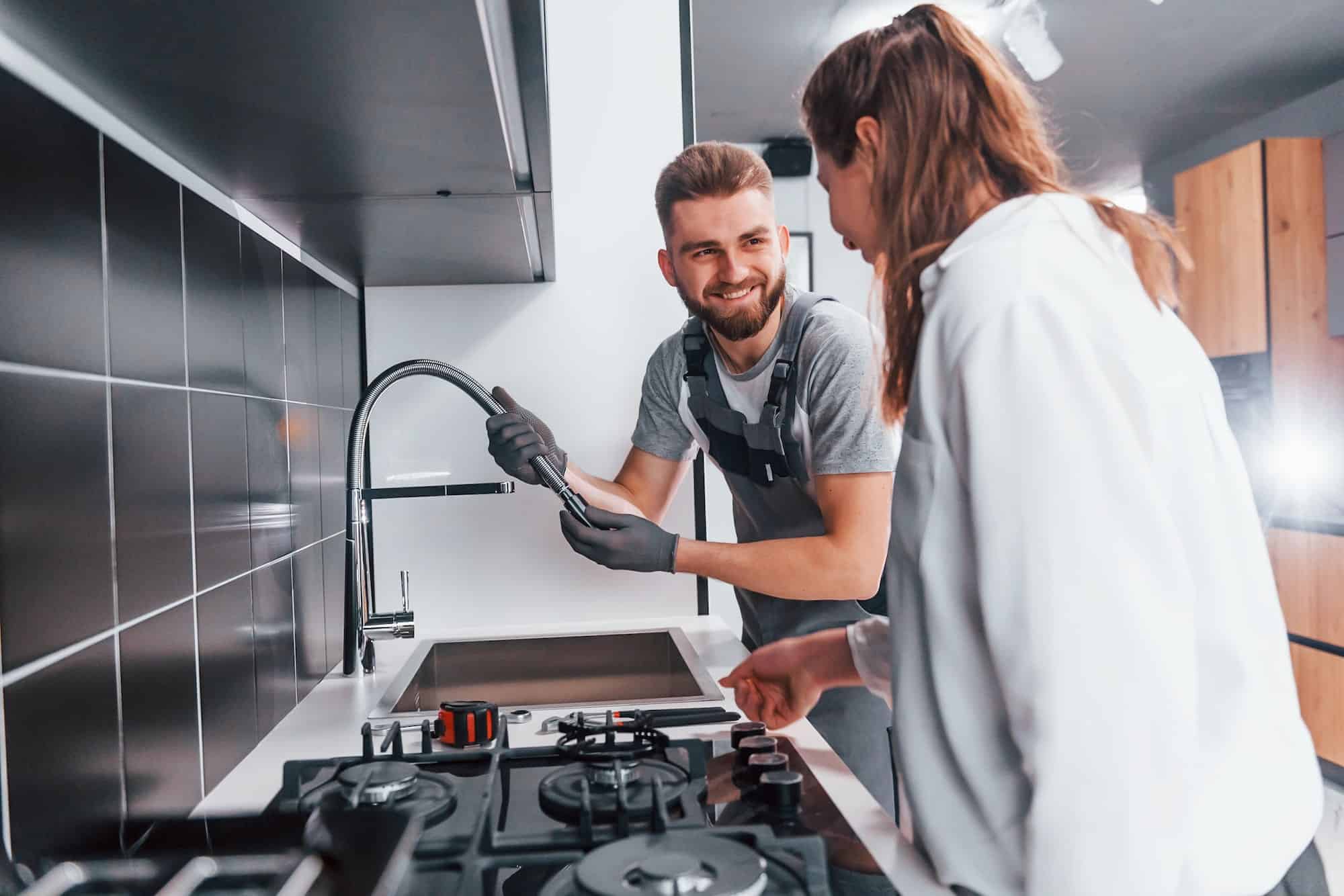 young-professional-plumber-in-grey-uniform-shows-results-of-work-for-housewife-on-the-kitchen.jpg young-professional-plumber-in-grey-uniform-shows-results-of-work-for-housewife-on-the-kitchen.jpg